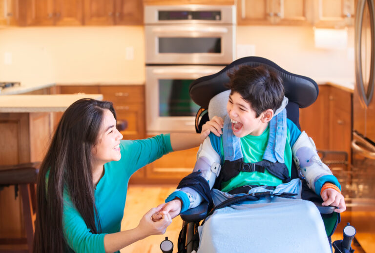 Nine,Year,Old,Disabled,Boy,In,Wheelchair,Laughing,With,Teen